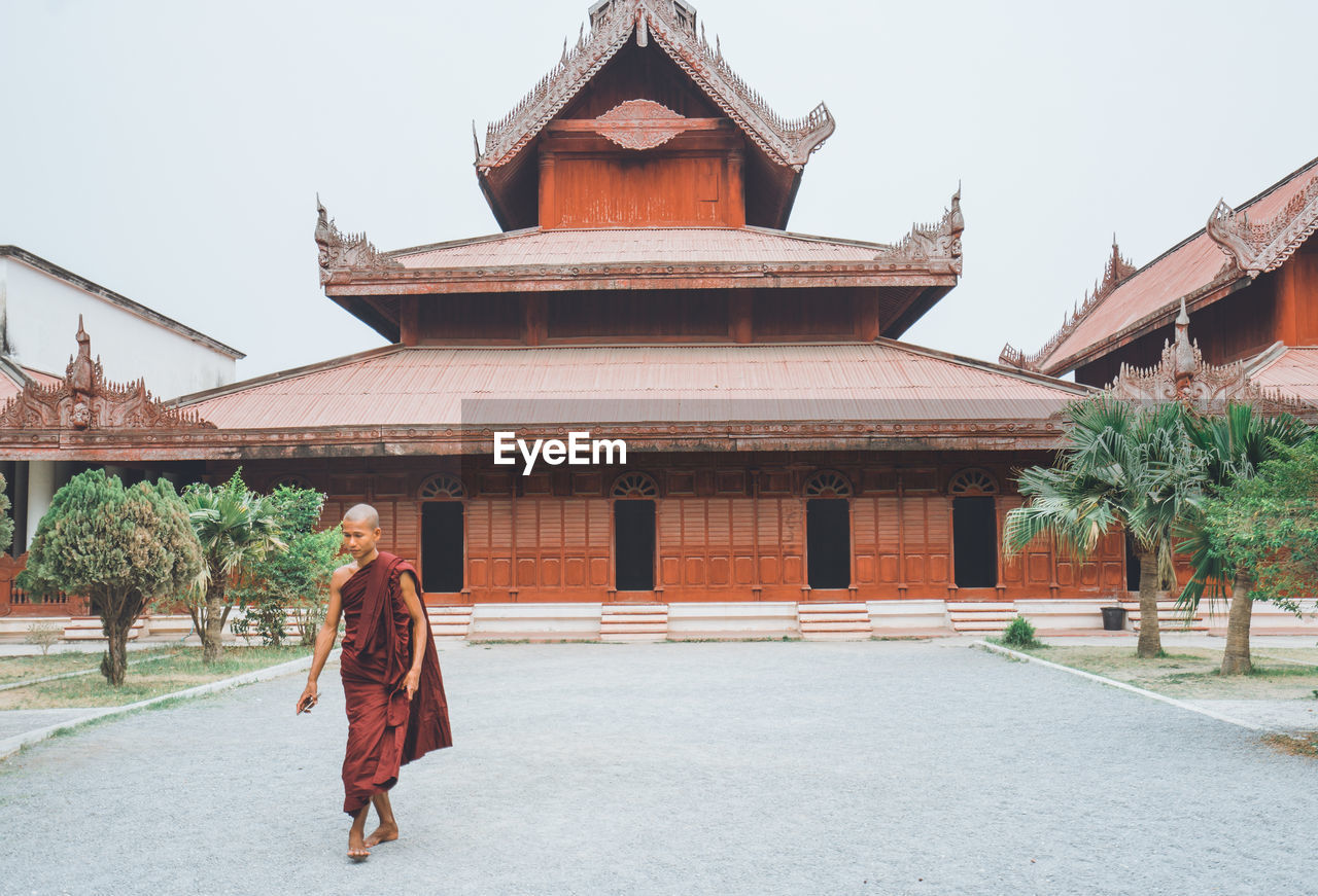 REAR VIEW OF A MAN WALKING IN TEMPLE