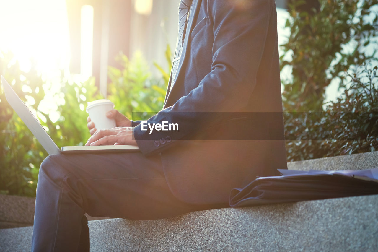 Midsection of businessman using laptop