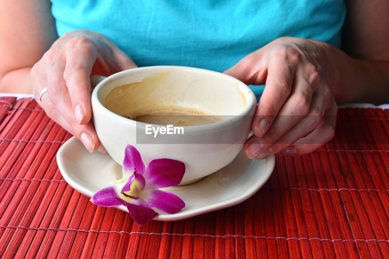 Woman holding coffee cup while sitting at table