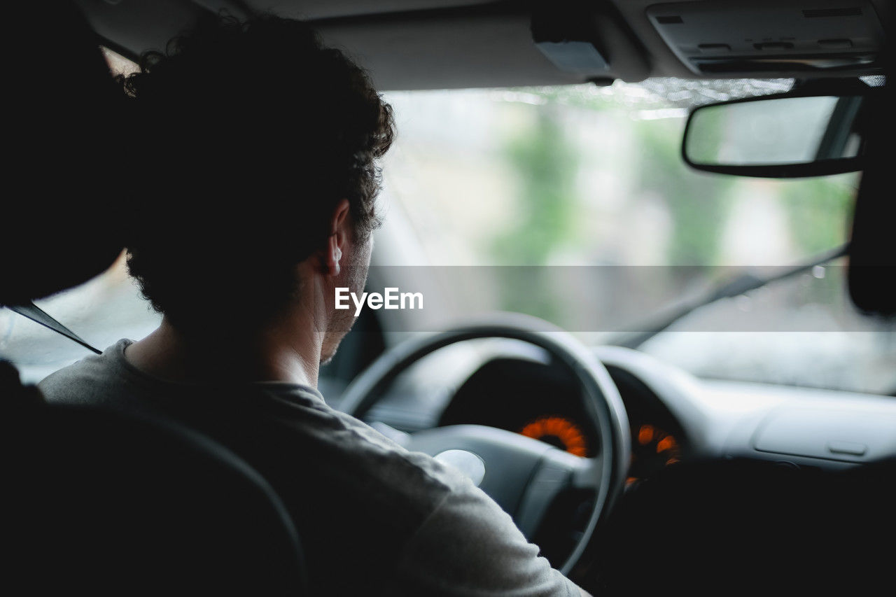 A young caucasian guy sits behind the wheel while driving a car.