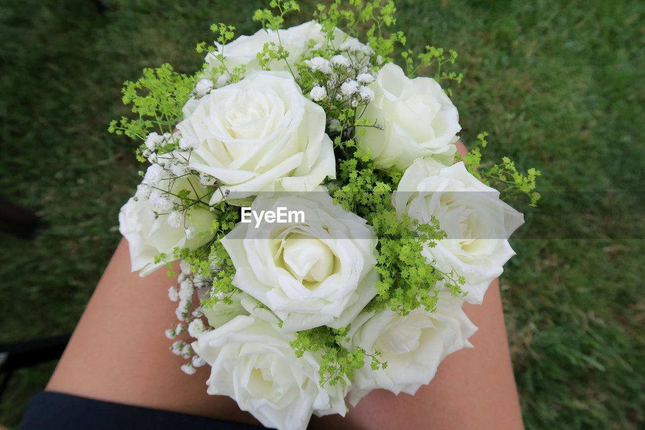CLOSE-UP OF HAND HOLDING WHITE ROSE BOUQUET