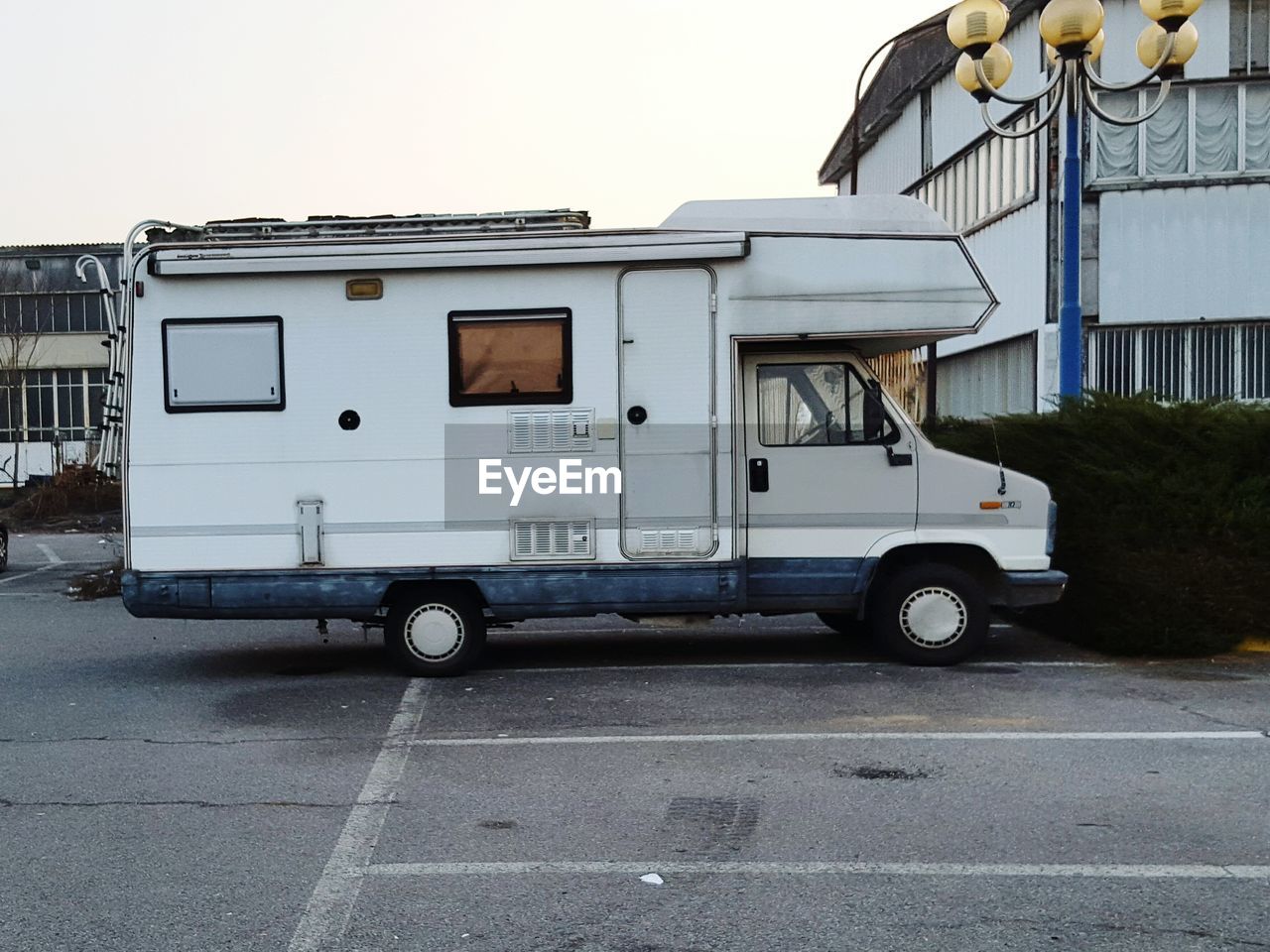 Motor home by house on road against sky