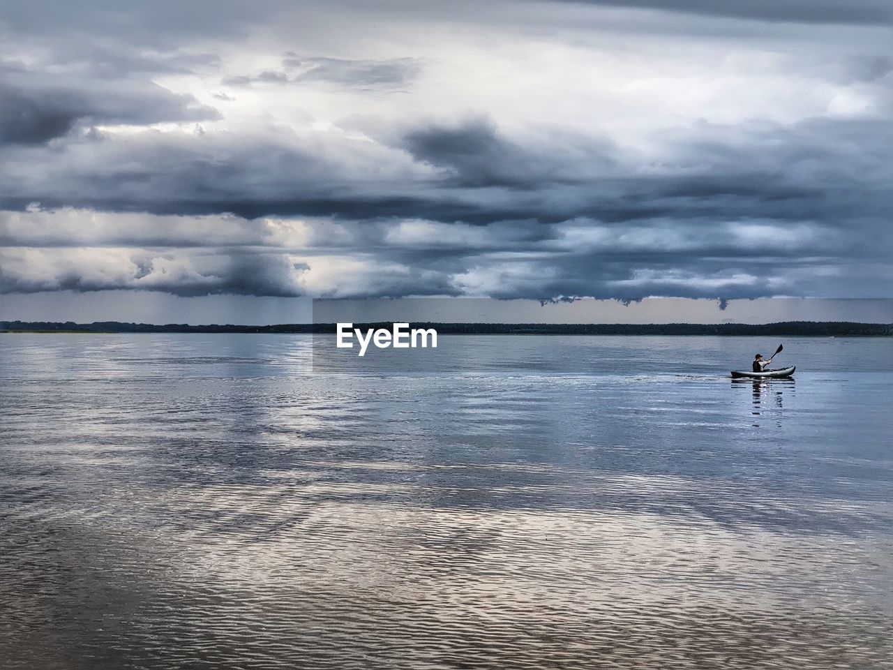 Scenic view of sea with man rowing boat against sky