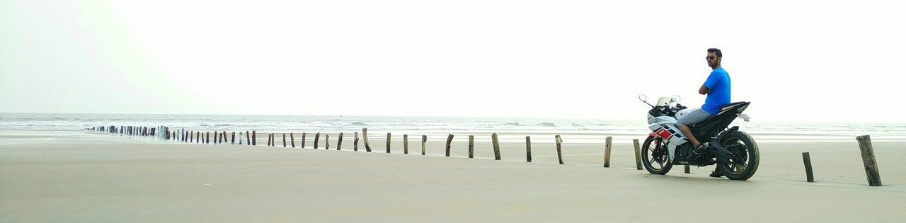 Panoramic shot of man sitting on motorcycle at mandarmani beach against sky