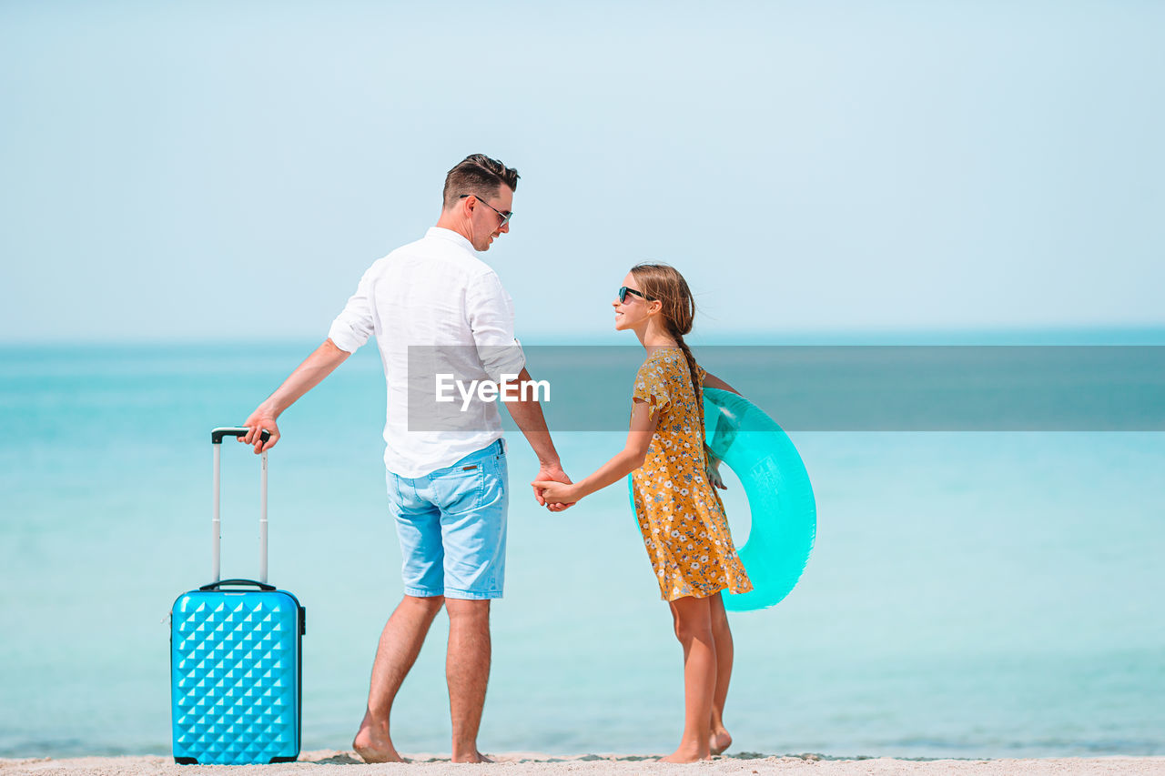 Full length of father and daughter standing on beach