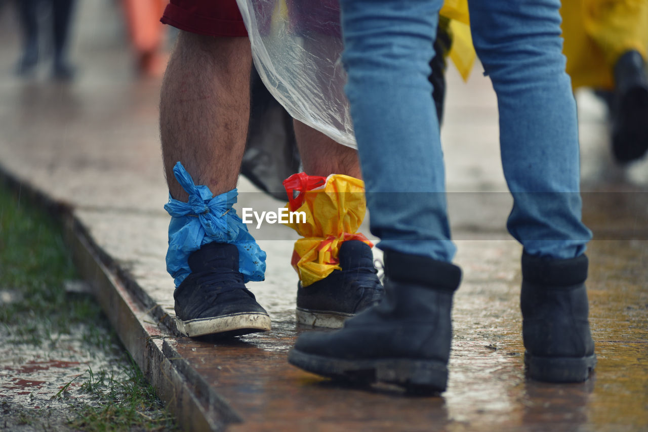 Low section of man tied polythene bag on leg while standing on street