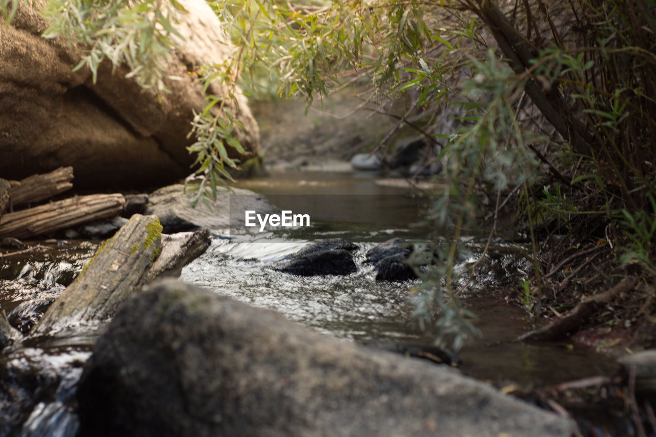 CLOSE-UP OF WATER FLOWING THROUGH ROCKS