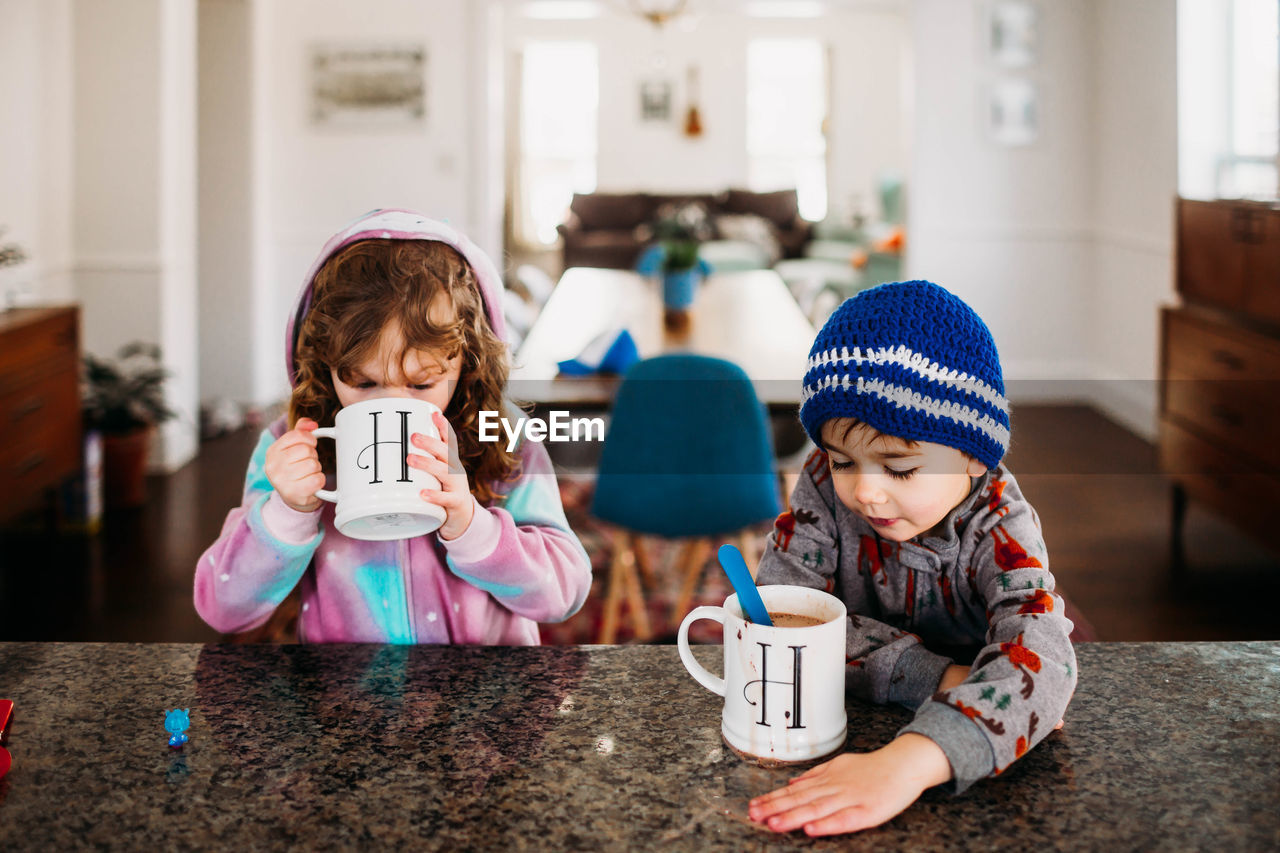 Young boy and girl drinking hot chocolate inside on a cold winter day
