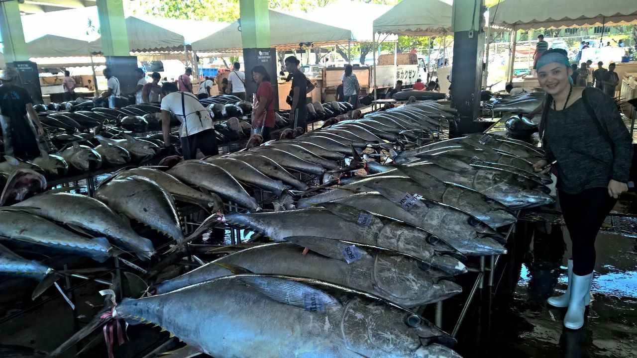 Full length of smiling young woman standing in fish market