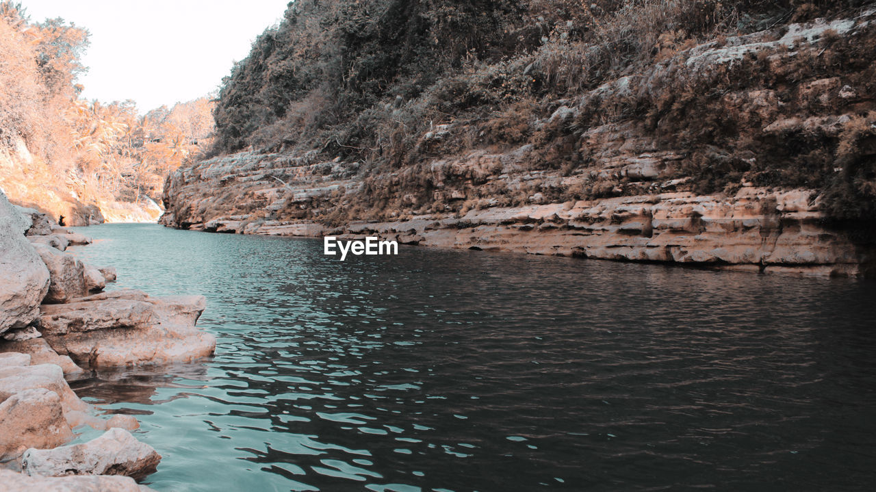 SCENIC VIEW OF ROCK FORMATION BY WATER AGAINST SKY