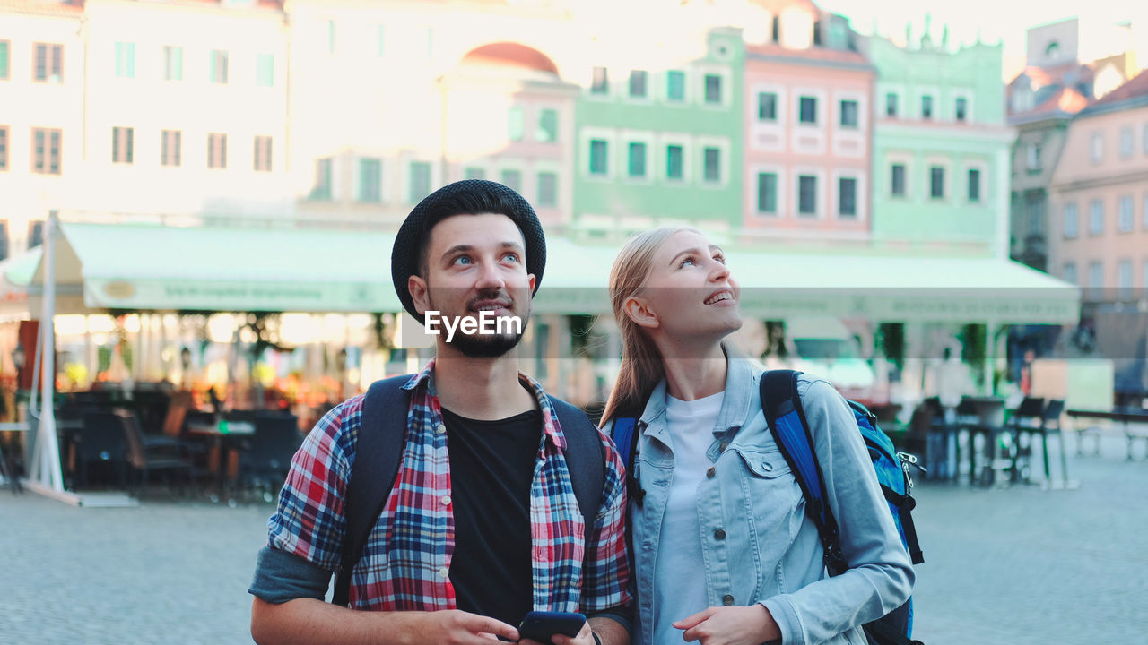 YOUNG COUPLE STANDING ON CITY STREET