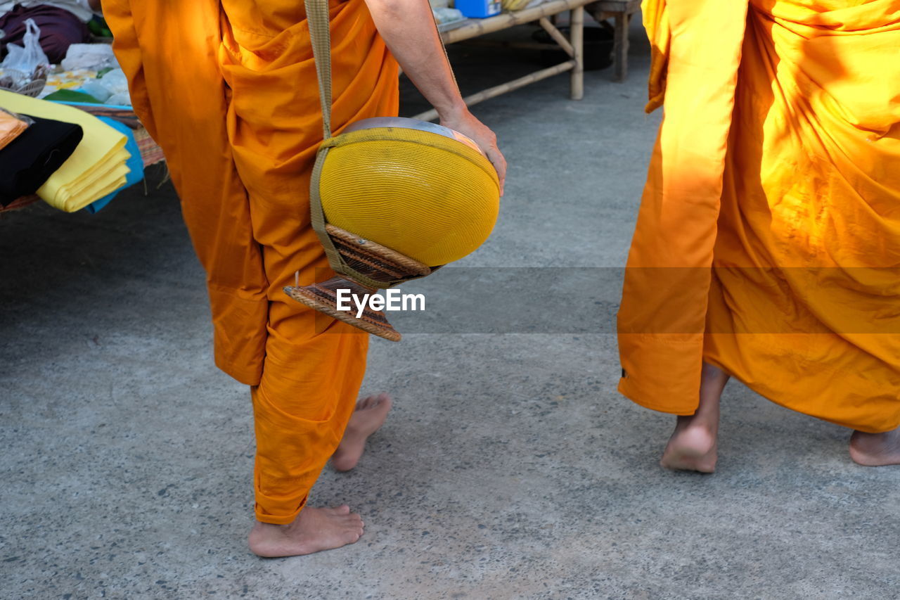 Low section of monk with bag walking on street