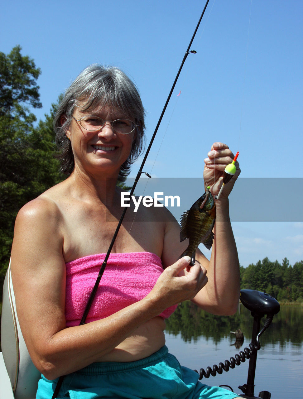 Portrait of senior woman holding fish on fishing line