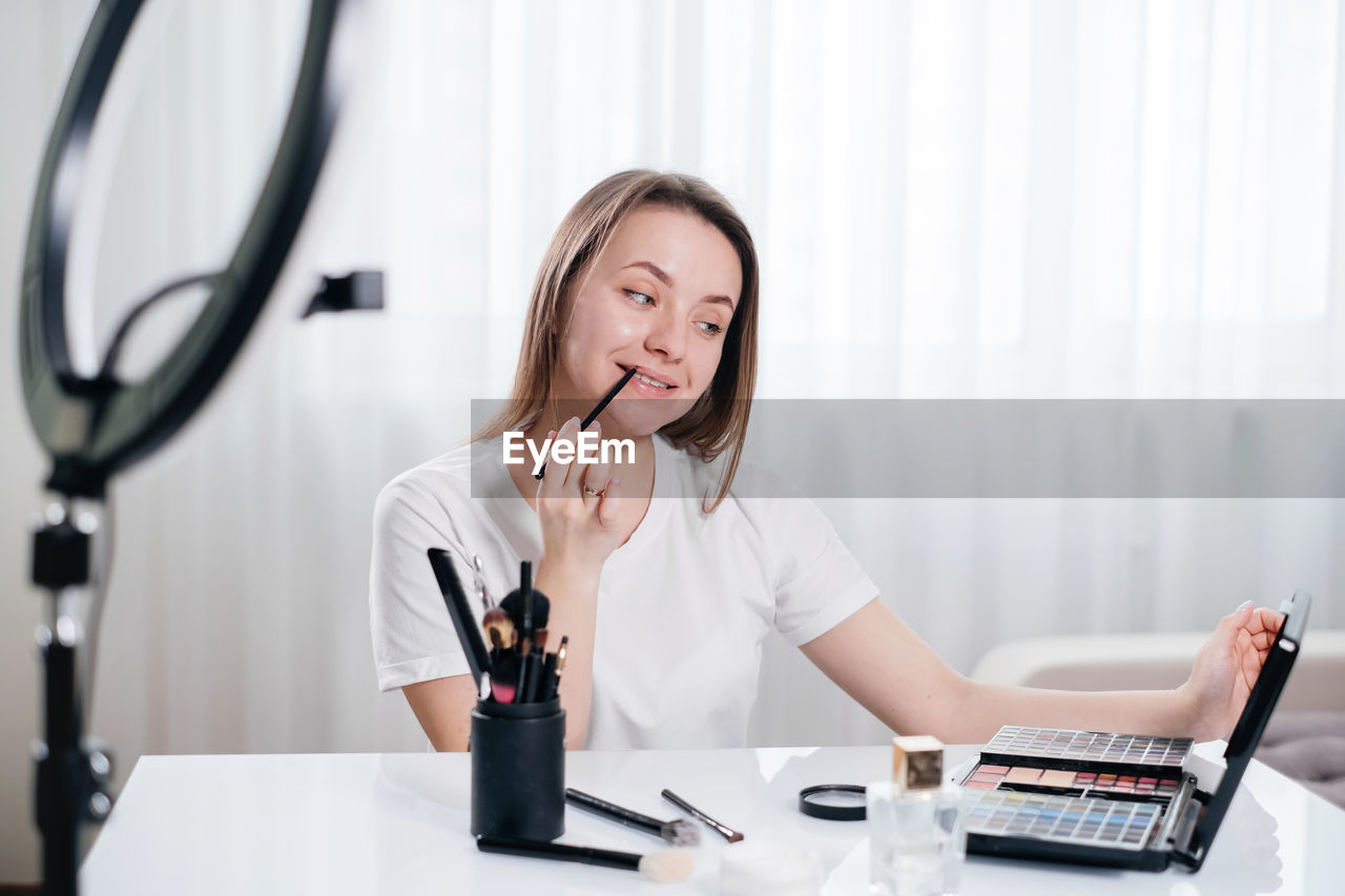 Woman beauty blogger recording vlog video at home about make-up and cosmetics. online influencer