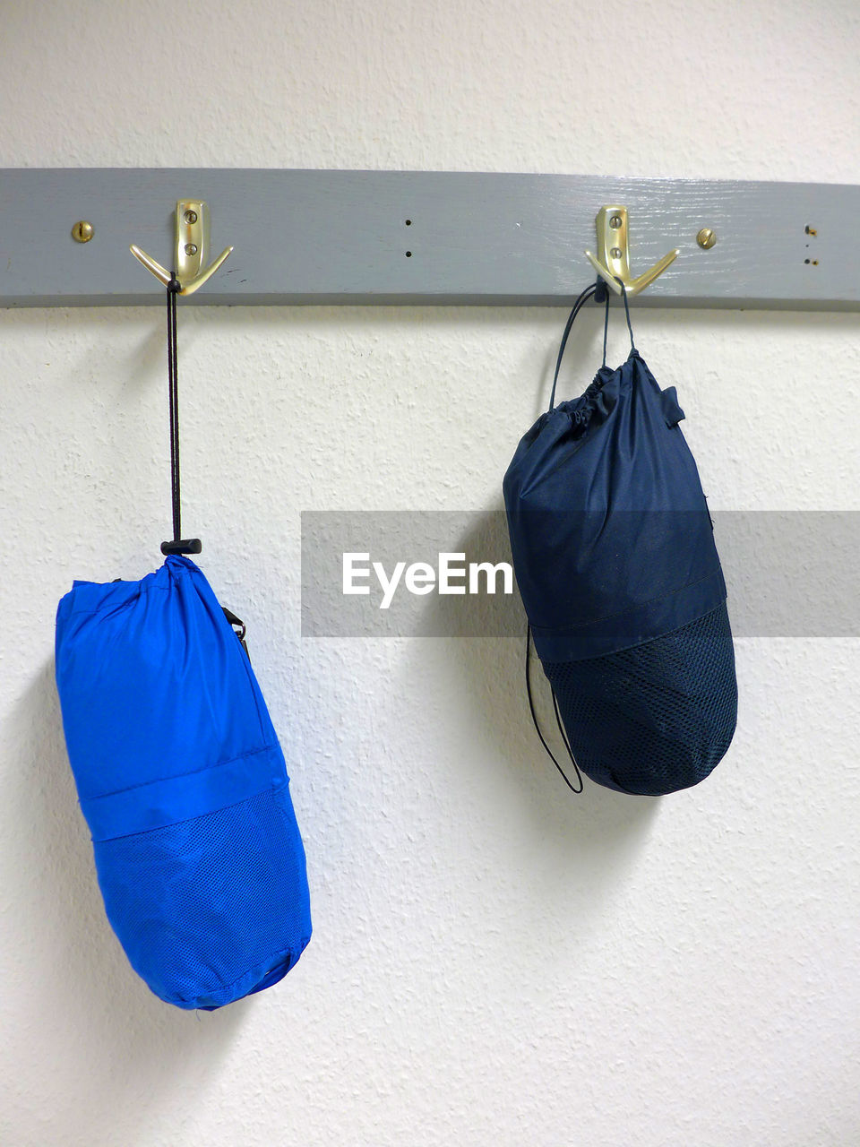 Boxing bags hanging on hooks against wall at home