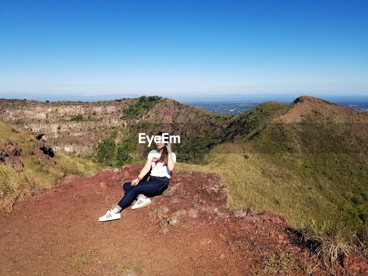 Full length of woman sitting on mountain against sky