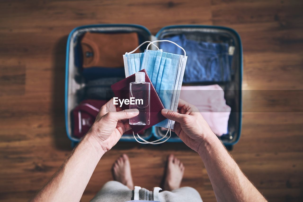 Preparing for travel in new normal. man packing passport, face masks and hand sanitizer.