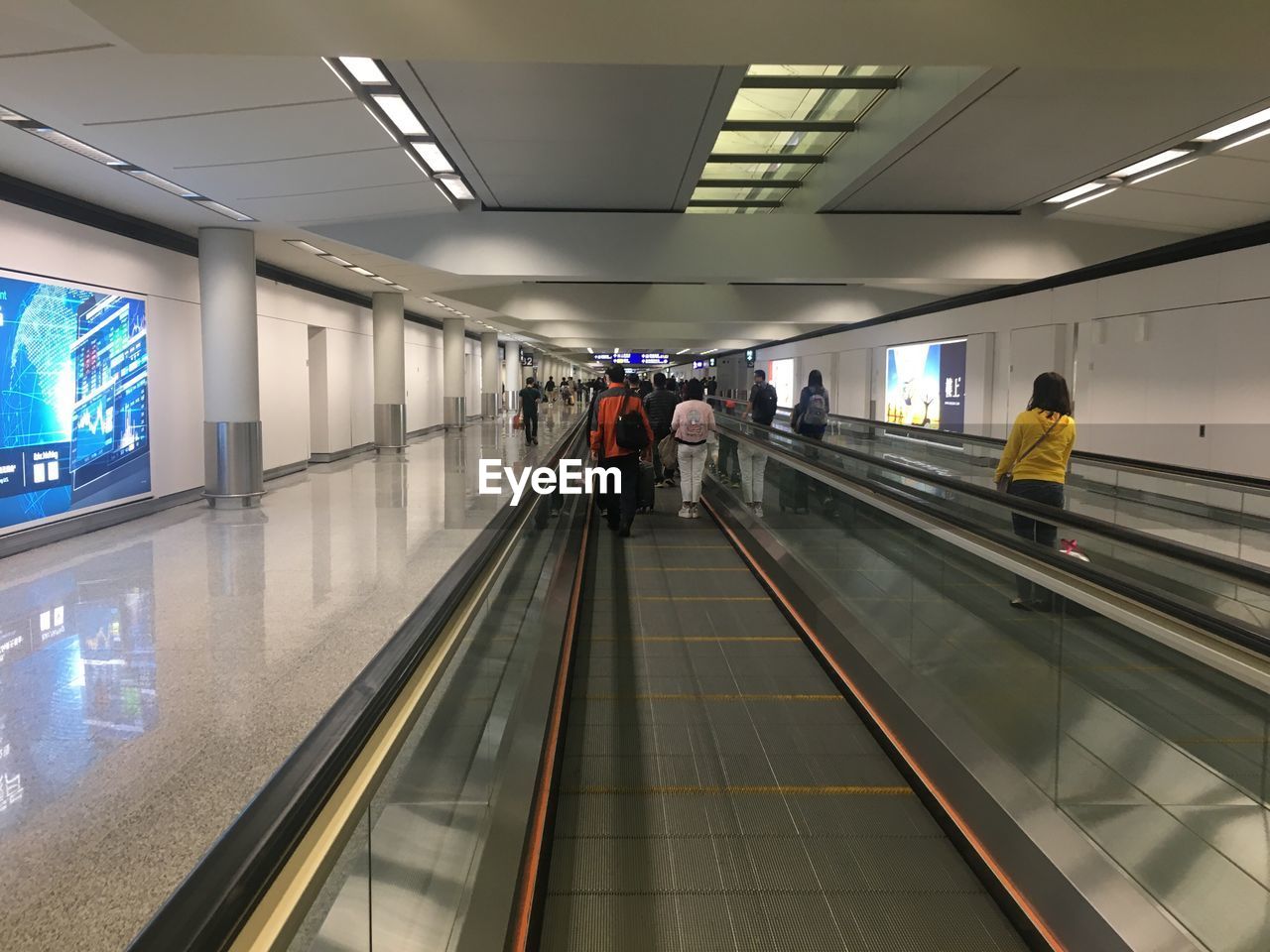 REAR VIEW OF PEOPLE WALKING IN ILLUMINATED UNDERGROUND