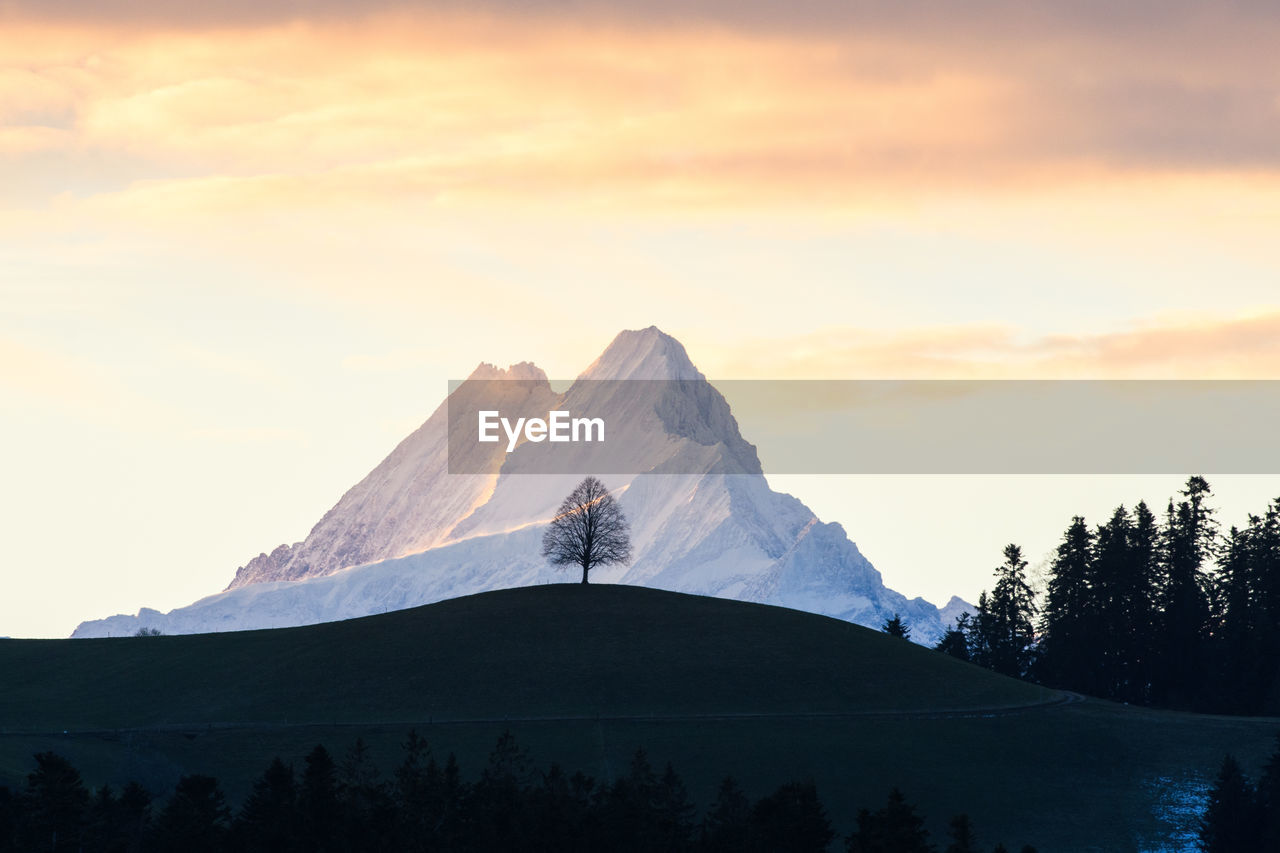 SNOW COVERED MOUNTAIN AGAINST SKY DURING SUNSET