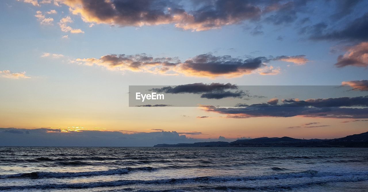 SCENIC VIEW OF BEACH AGAINST SKY AT SUNSET