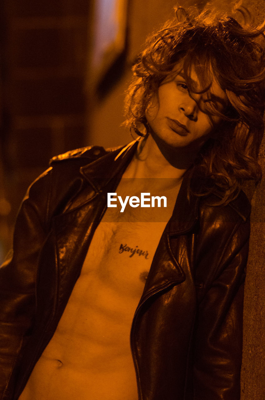 Portrait of young man with long hair wearing unbuttoned leather jacket