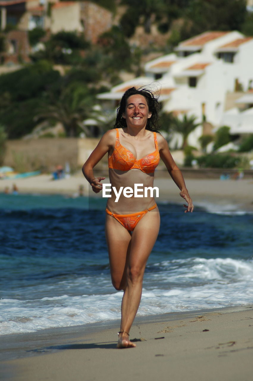Full length of smiling woman running on beach