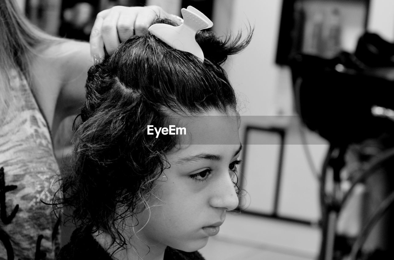 Midsection of mother holding daughter hair at home