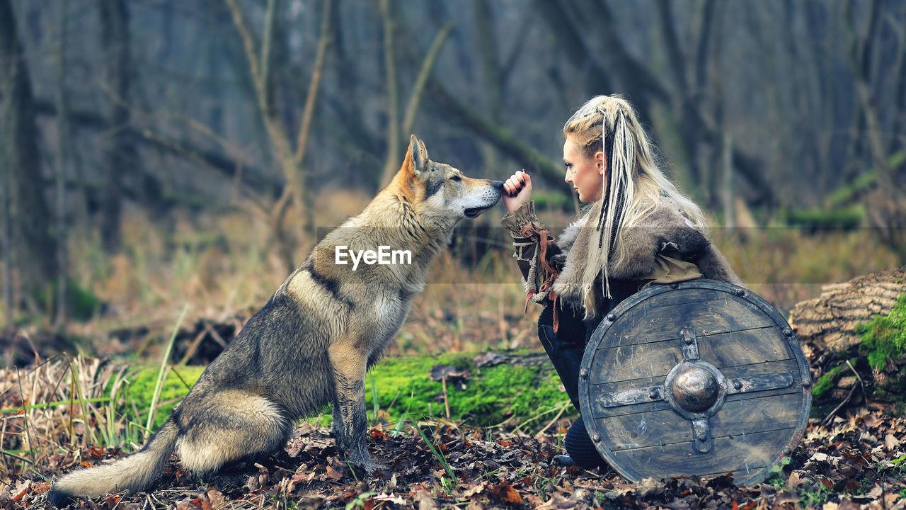 Woman looking at wolf in forest