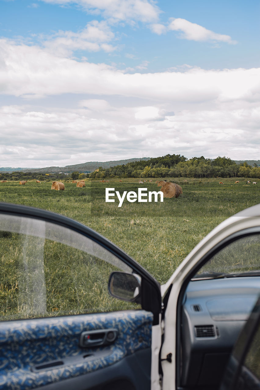 View of the autumn field with haystacks from behind the car door. the atmosphere of car trips