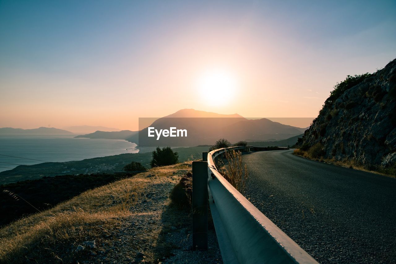 Road leading towards mountains against sky during sunset