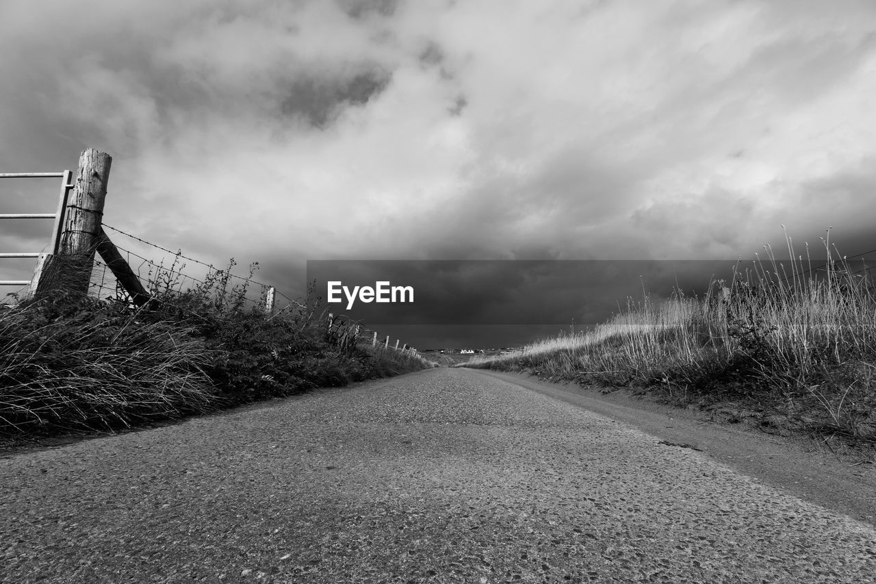 Road amidst field against sky