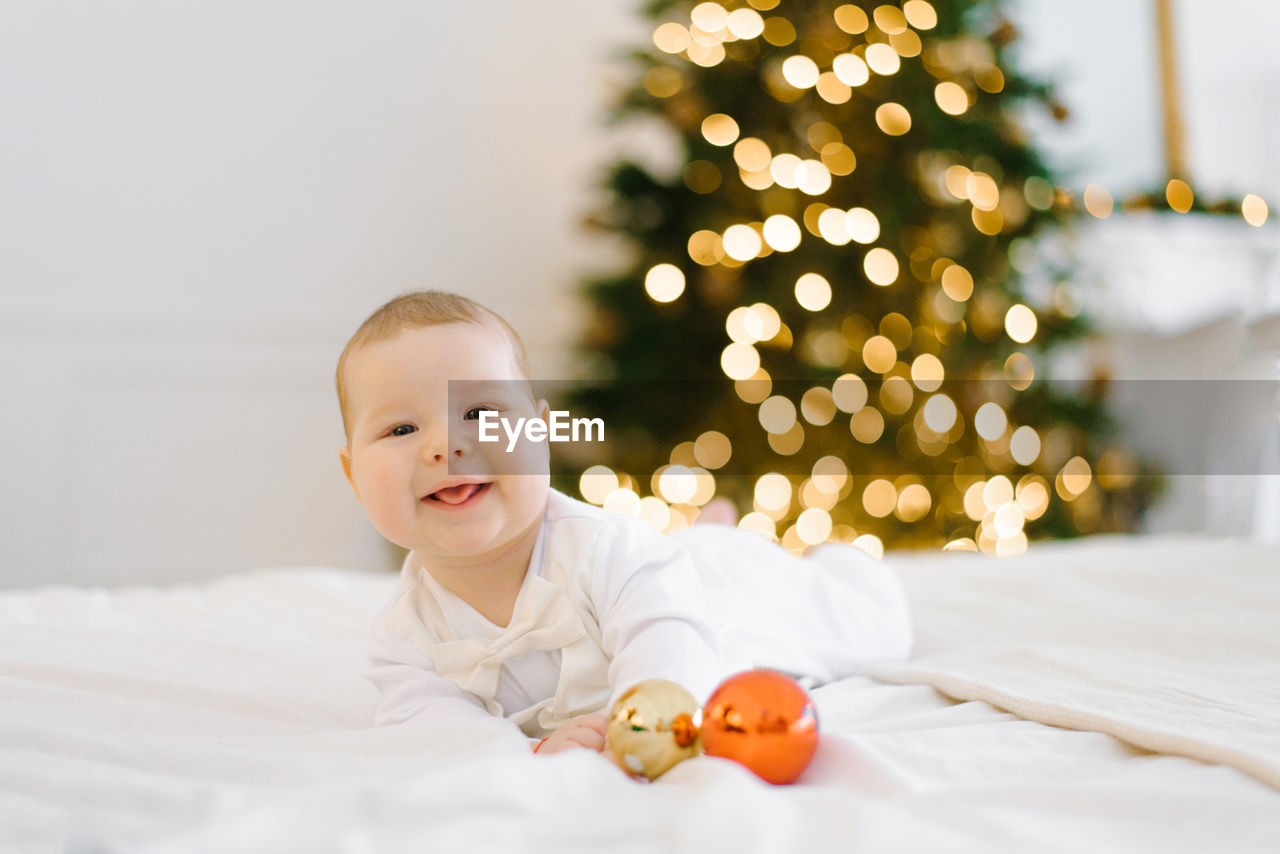 A child lies on a bed in a bedroom decorated for christmas and new year and laughs