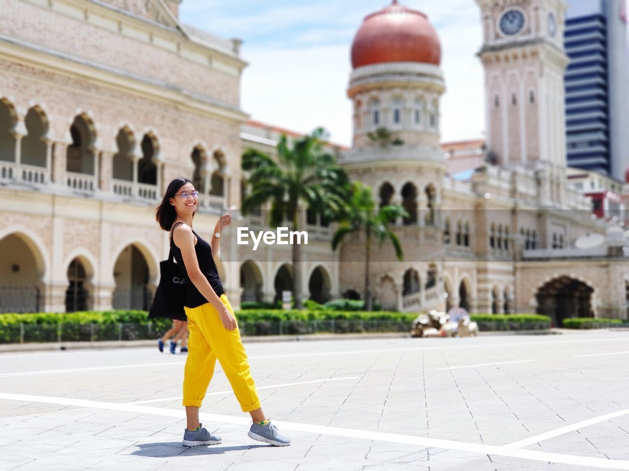 Side view full length of young woman standing on street in city