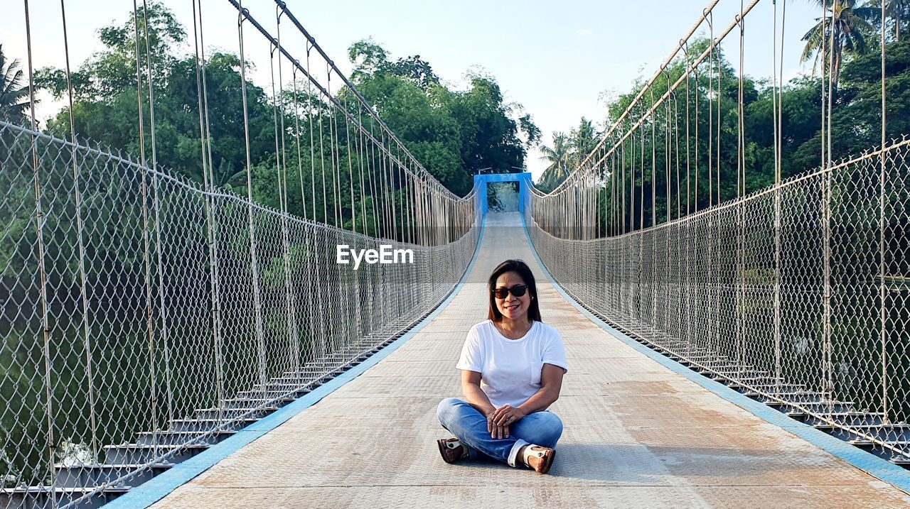 Full length of woman sitting on footbridge