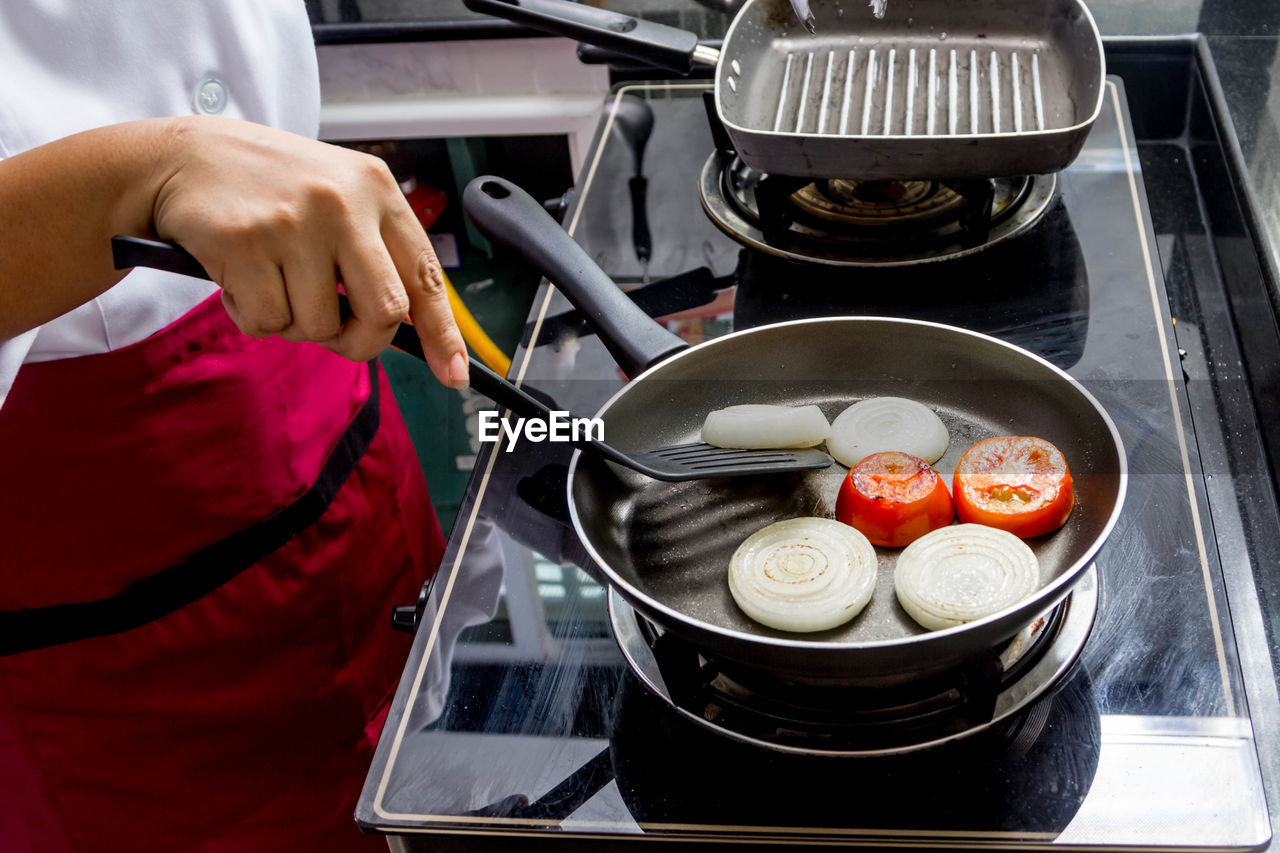 MIDSECTION OF MAN PREPARING FOOD IN KITCHEN