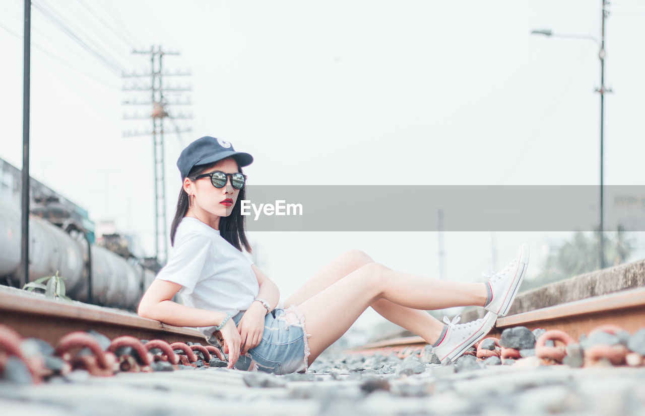 Portrait of young woman sitting on railroad track