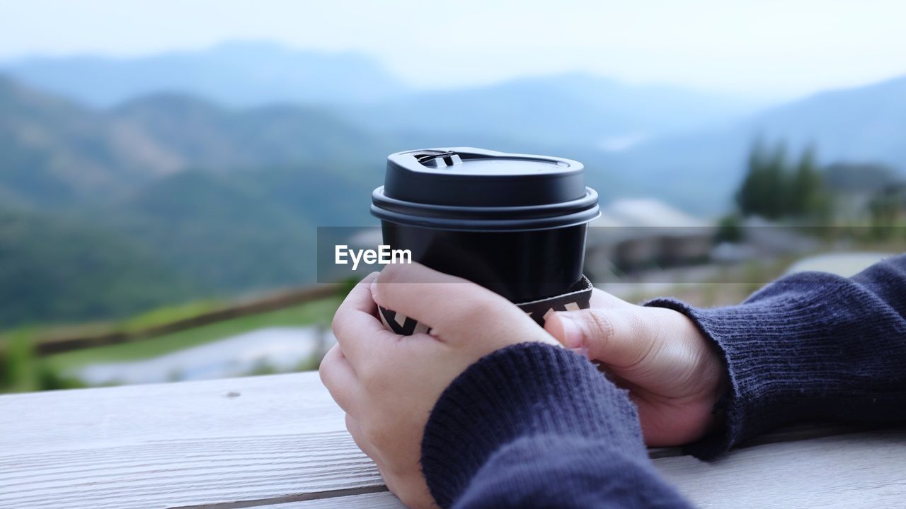 Close-up of person hands holding disposable coffee cup