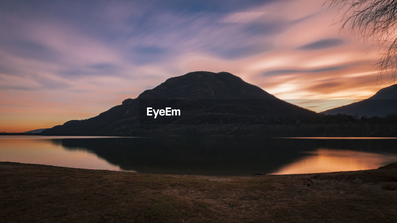 Scenic view of lake by mountains against sky during sunset