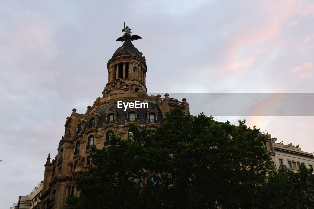 LOW ANGLE VIEW OF BUILDING AGAINST SUNSET SKY