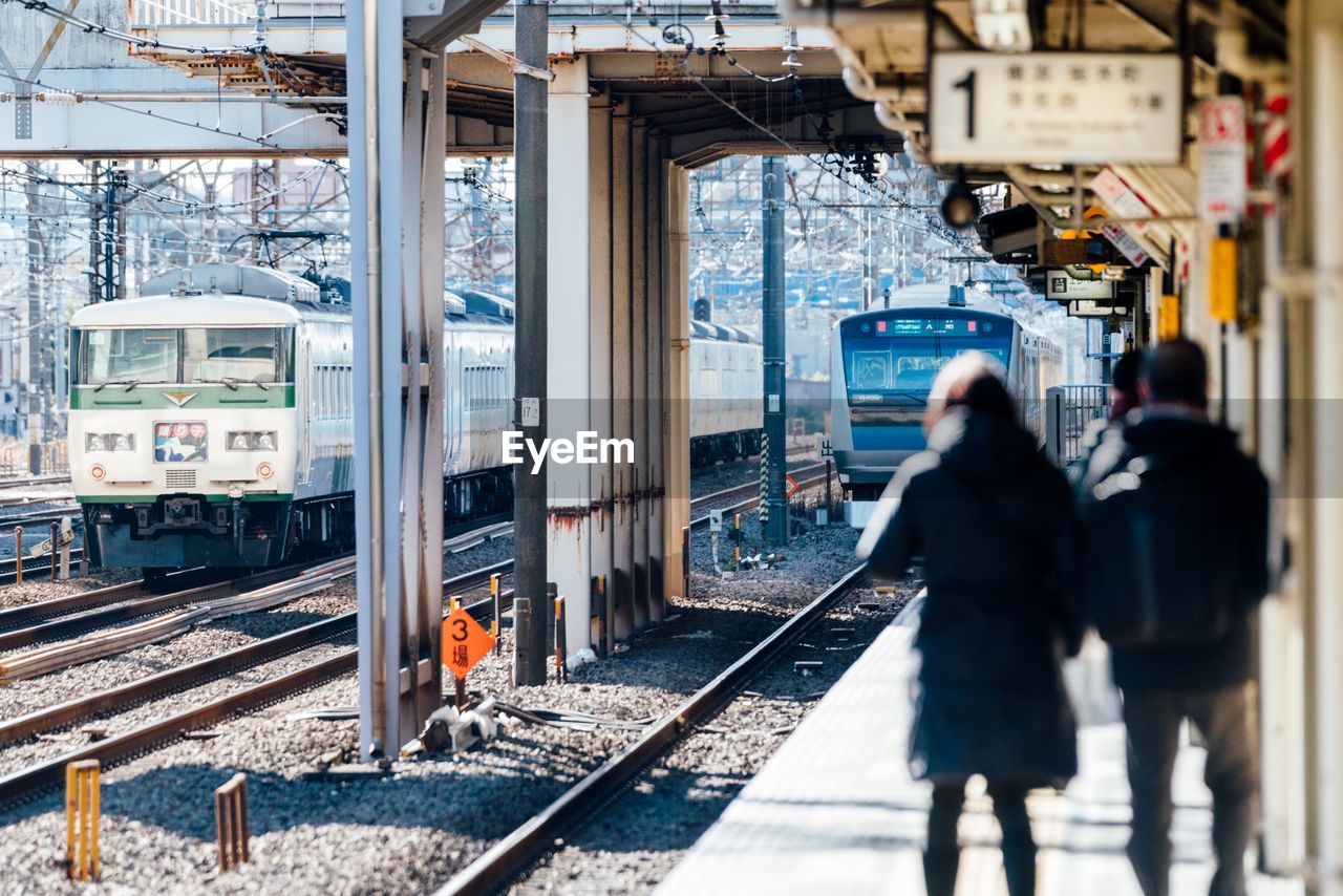 REAR VIEW OF PEOPLE ON TRAIN AT RAILROAD STATION