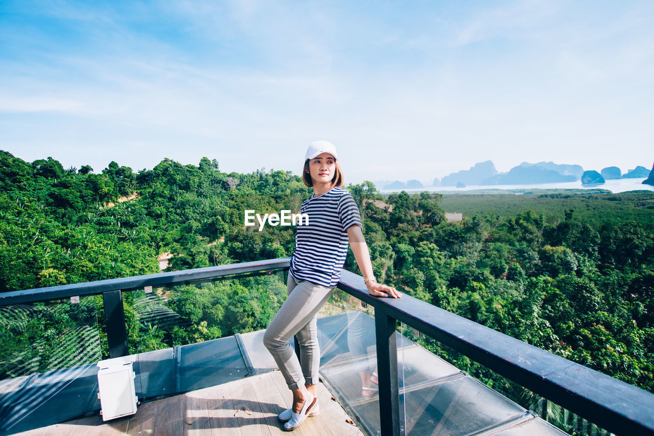 Young woman looking away while standing against railing on building terrace