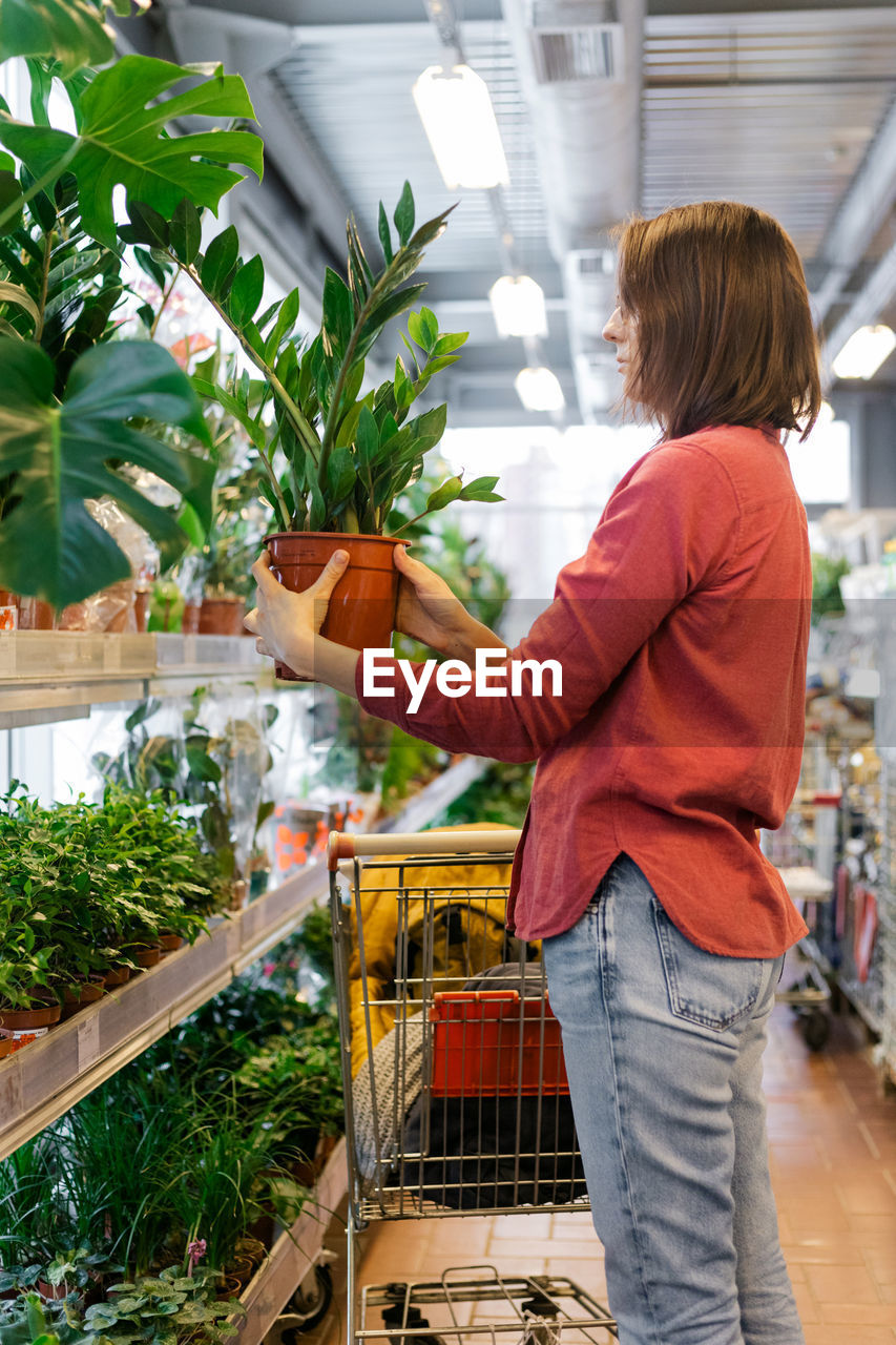 Midsection of woman standing by store buying plants