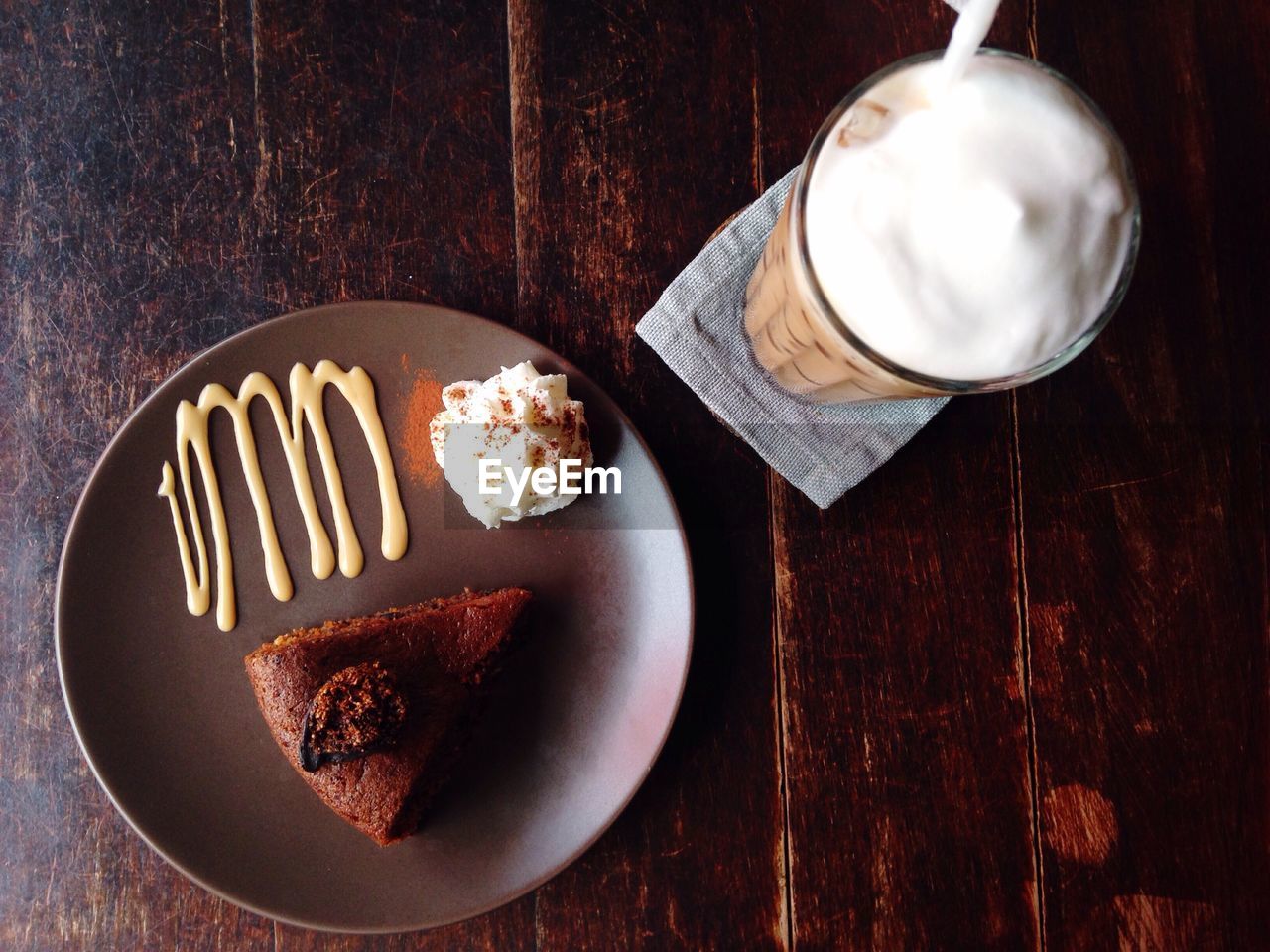 High angle view of baked pastry cake in plate along with frothy drink