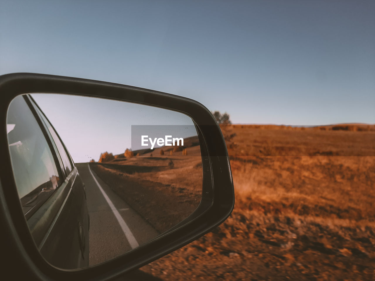Road seen through side-view mirror of car