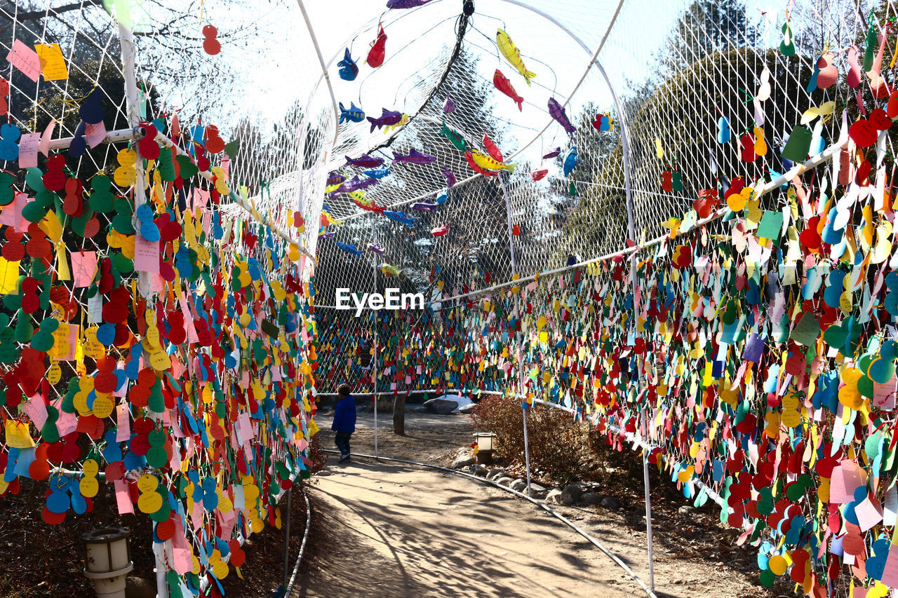 Colorful papers tied to fence at walkway