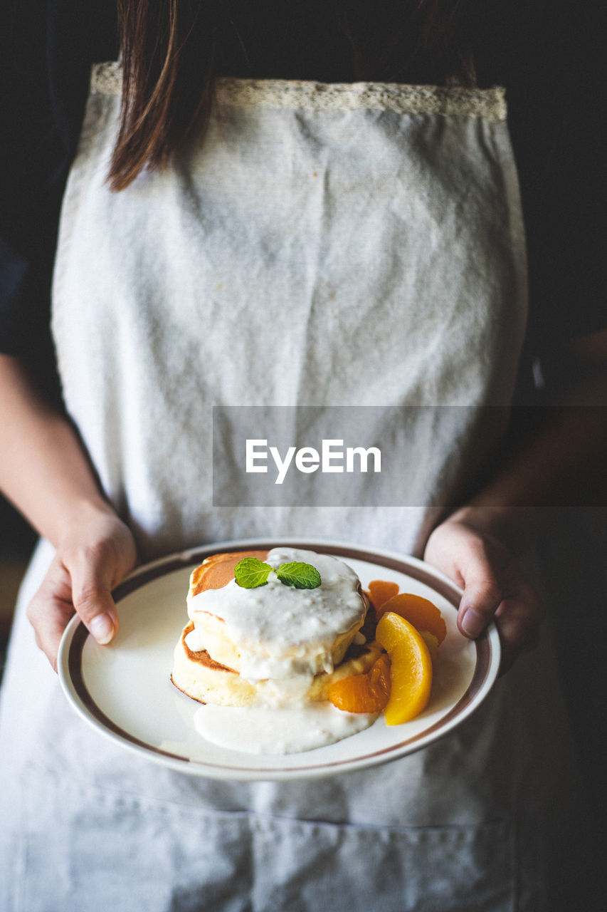 Midsection of woman holding breakfast in plate