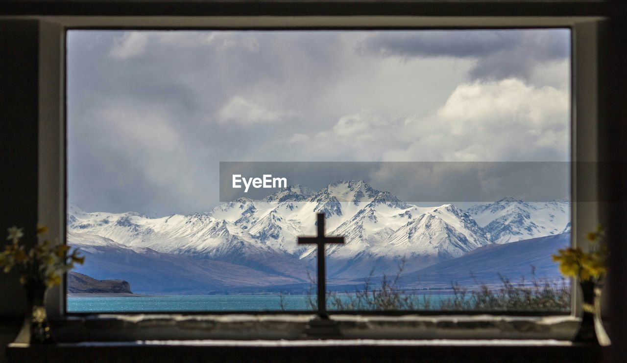 Lake tekapo and snowcapped mountains seen through church window