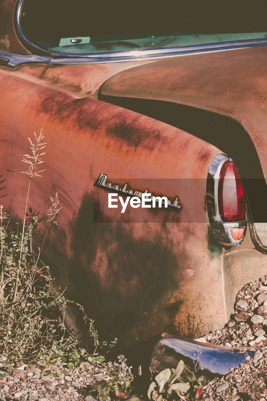 Close-up of abandoned car parked in field