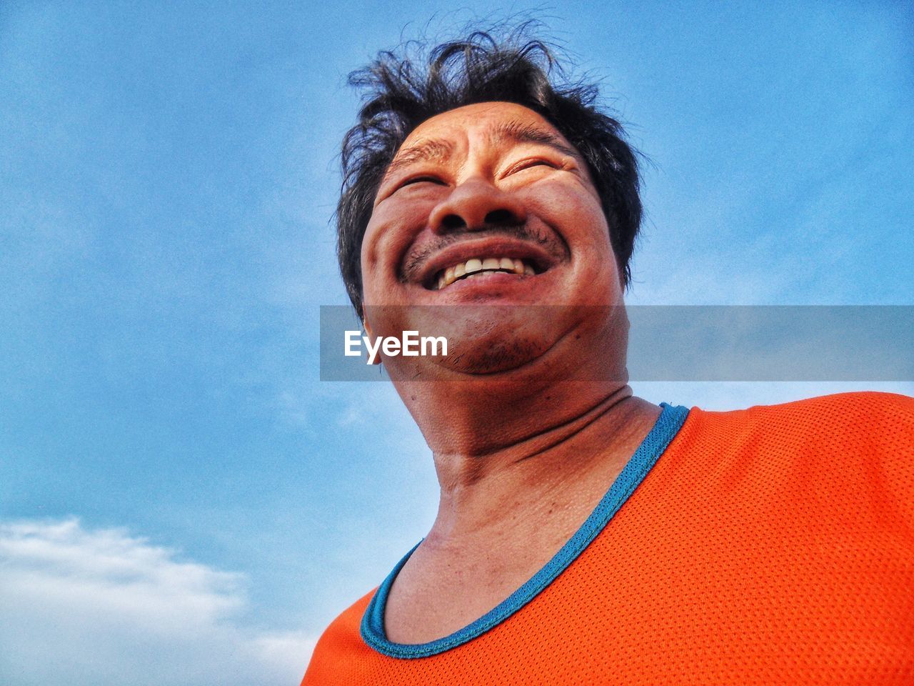 Low angle view of smiling mature man against sky