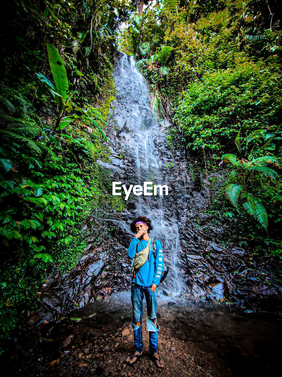 Man standing by waterfall in forest